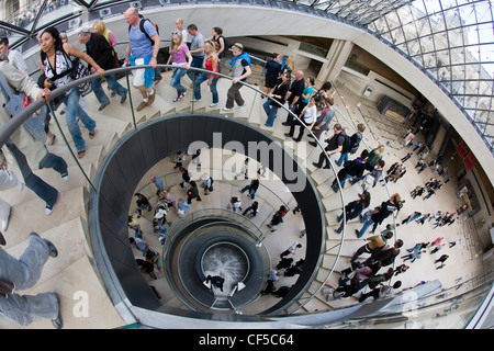Crowds of tourists leaving the Louve Musuem in Paris via the spiral staircase Stock Photo
