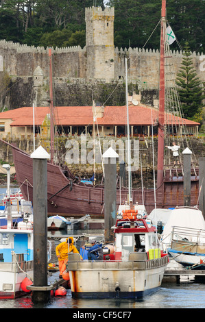 Traditional fishing boats in front of the Monte Real castle and La Pinta caravel. Baiona. Galicia, Spain. Stock Photo