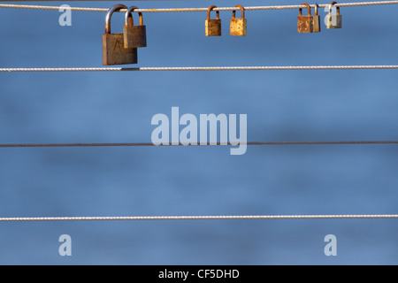 A few of padlocks hanging on one cable in Rewal, Poland. Stock Photo
