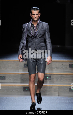 Byblos Milan Ready to Wear Spring Summer Model wearing narrow legged grey leather shorts, black leather belt, grey patterned Stock Photo