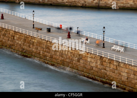 People on Whitby Pier. A large portion of Bram Stoker's famous novel was set in Whitby, describing Dracula's arrival in Britain Stock Photo