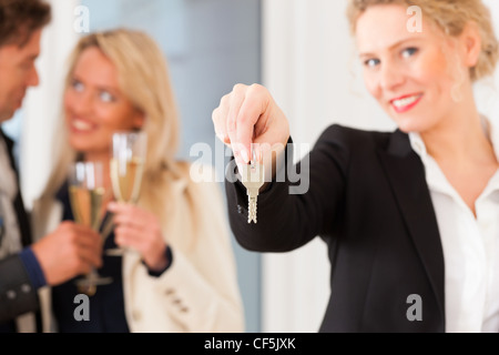 Real estate market - young couple looking for real estate to rent or buy; they celebrate with champagne and get the keys Stock Photo