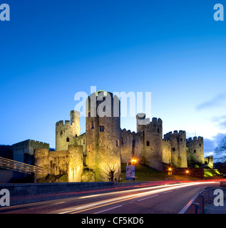 Conwy Castle lit up at dusk. The castle was an important part of King Edward I's plan of surrounding Wales in 'an iron ring of c Stock Photo