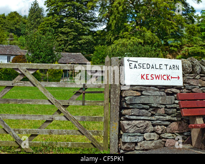 A hand carved sign with directions to Easedale Tarn and Keswick on a stone wall. Stock Photo