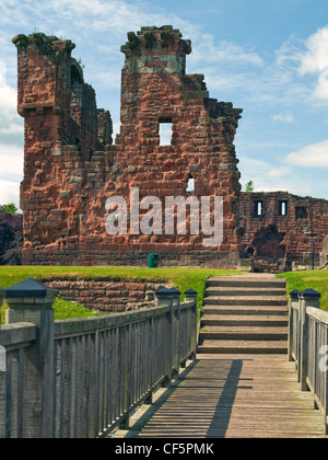 A wooden footbridge over a moat leading to the ruins of Penrith Castle, once a royal fortress for Richard, Duke of Gloucester be Stock Photo