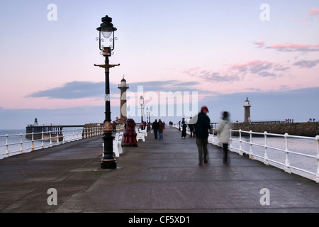 People on Whitby pier at sunset. A large portion of Bram Stoker's famous novel was set in Whitby, describing Dracula's arrival i Stock Photo
