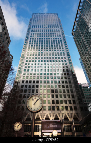 Looking up past clocks in Cabot Square to the Canary Wharf Tower (One Canada Square) the UK's tallest building. Stock Photo