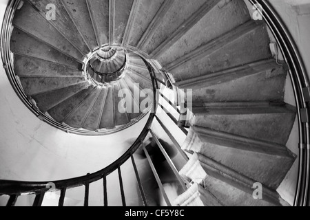 A person descending the spiral stairs inside the Monument in the City of London. The Monument is a colossal Doric column 61 mete