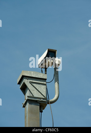 A CCTV (closed circuit television) camera on top of a tall pole surveying the traffic passing along the M25 in Essex. Stock Photo