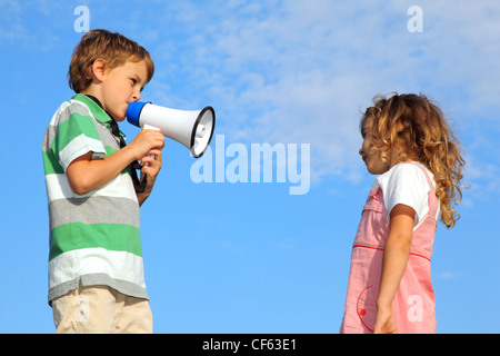 The little boy, on the nature, does reprimand to the girl through a loudspeaker. Stock Photo