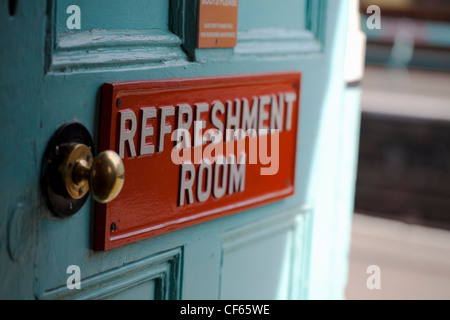 A sign reading 'Refreshment Room' on a door leading off a train station platform. Stock Photo