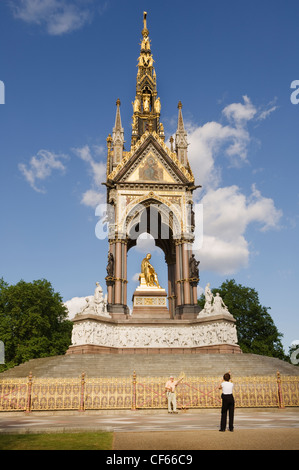 A tourist standing for a photograph in front of the Albert Memorial in Hyde Park. Stock Photo
