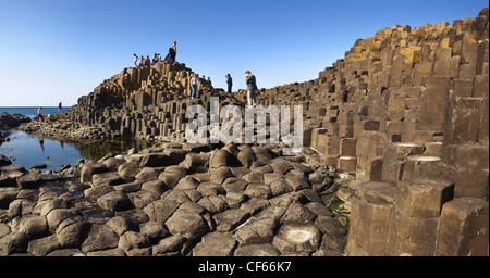 Tourists exploring the interlocking basalt columns of the Giants Causeway,  a World Heritage Site and National Nature Reserve. Stock Photo