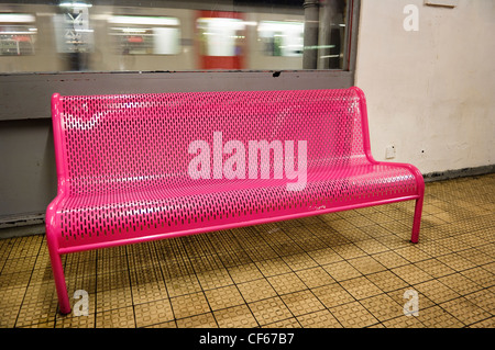 A District line underground train speeds past a pink bench in a waiting room at Barking Station. Stock Photo