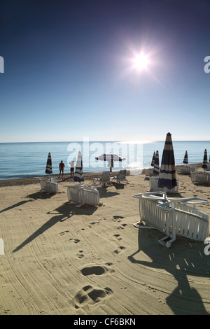 Couple stands near water in  morning on  beach which empty sun lounger are built on Stock Photo