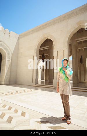 beautiful european woman with kerchief on her head in arab country. she is inside Grand Mosque in Oman. Stock Photo