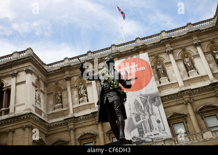 A sculpture of Sir Joshua Reynolds outside the Royal Academy of Arts in front of a large banner advertising the annual summer ex Stock Photo
