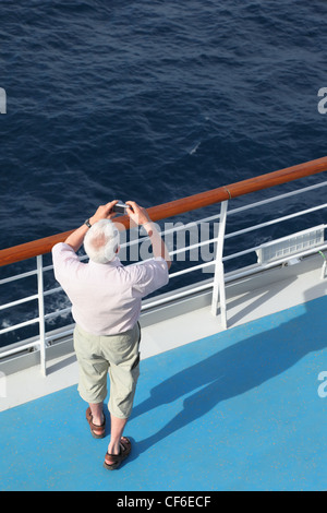 man with compact photo camera standing on deck of cruise ship and shooting. Stock Photo