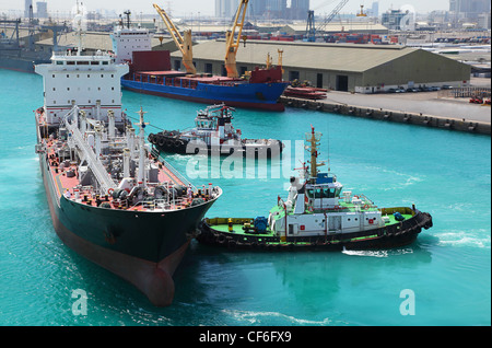 Two small boats docked to industrial ship in port at sunny day Stock Photo