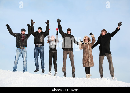 Young people jump in winter on snow and lift hands upwards