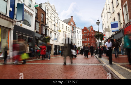 people quickly going on small, narrow street in cloudy weather Stock Photo