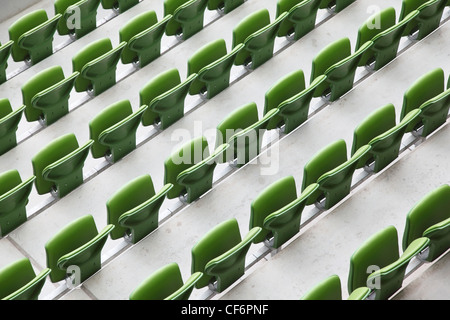 Many rows of green, plastic, folding seats in a big empty stadium. Stock Photo