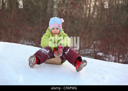 Girl go downward from  hill on the piece of cardboard Stock Photo