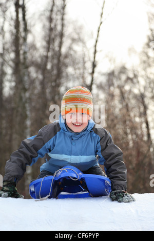 Boy intend  drive from  hill in winter on sledges and push off hands Stock Photo