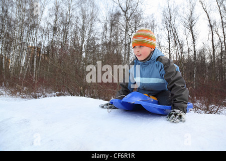 Boy by push off  intend  drive from  hill in winter on sledges Stock Photo