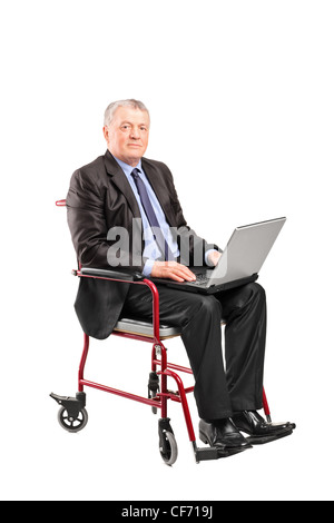 Mature businessman in a wheelchair working on a laptop isolated on white background Stock Photo