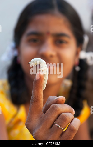 Indian girl with silkworm on her finger. Andhra Pradesh, India Stock Photo