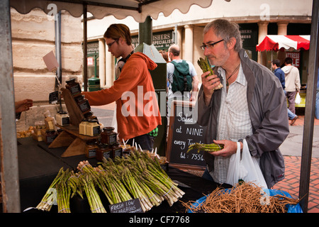 UK, Gloucestershire, Stroud, Union Street, weekly farmer’s market man sniffing asparagus Stock Photo