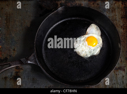 One egg frying in a cast iron skillet. Stock Photo