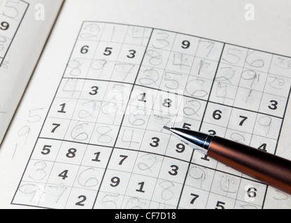 Pencil or pen resting on completed sudoku puzzle in book Stock Photo