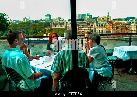 LONDON, Great Britain, UK - Group Young Adults Chatting at Table in the 'Oxo Restaurant', Terrace with Skyline, trendy restaurant, restaurant view scenic people eating Stock Photo