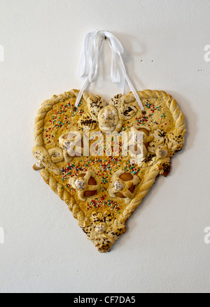 Italian Easter bread in the form of a heart sprinkled with coloured sugar beads and incorporating whole eggs. Stock Photo