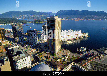 An aerial view of downtown Vancouver's waterfront in British Columbia, Canada, looks past tall buildings and boat docks to the North Shore Mountains. Stock Photo