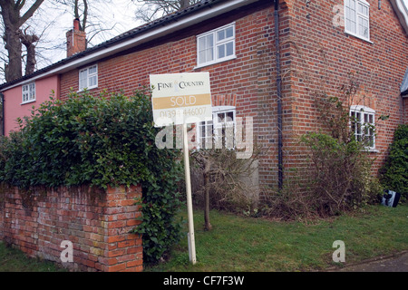 Sold estate agent's sign outside rural semi detached house Stock Photo
