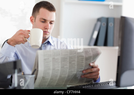 Businessman having a coffee while reading the newspaper Stock Photo
