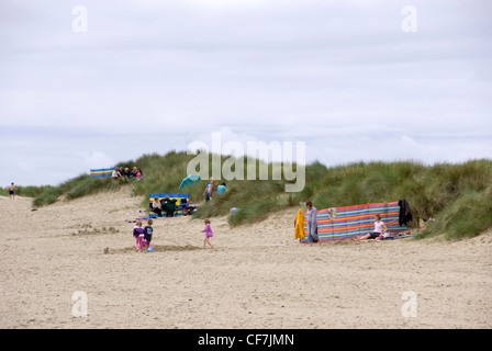 Families Playing in the Shelter of the Sand Dunes of Aberdovey Beach on an Overcast & Windy Summer Day, Aberdyfi, Wales, UK Stock Photo
