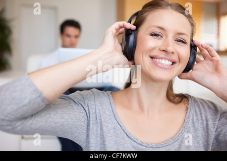 Woman with headphones on with man sitting behind her on the sofa Stock Photo