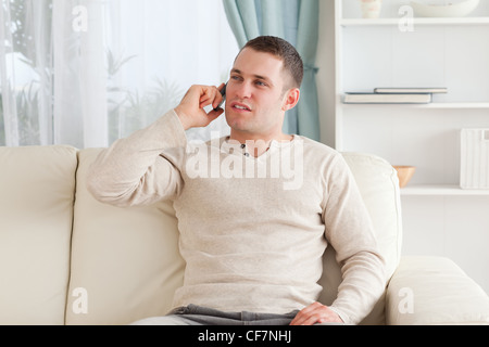 Young man on the phone while sitting on his couch Stock Photo