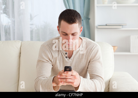 Man sending text messages while sitting on his couch Stock Photo