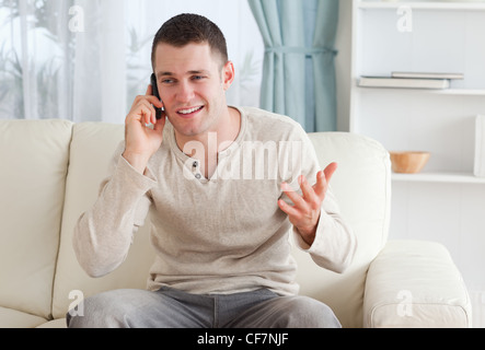 Man talking through the phone while sitting on a couch Stock Photo