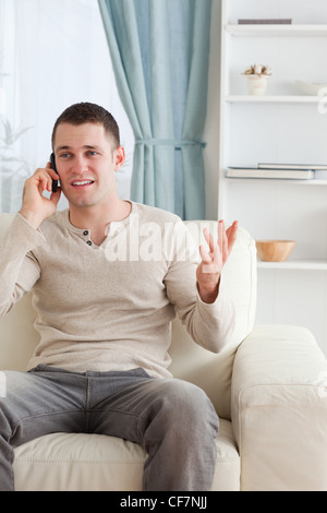 Portrait of a man talking through the phone while sitting on a couch Stock Photo