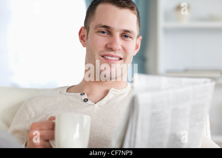 Smiling man having a tea while reading the news Stock Photo