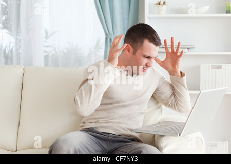 Unhappy man using a laptop Stock Photo