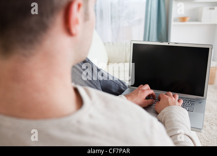 Man lying on his couch while using a laptop Stock Photo