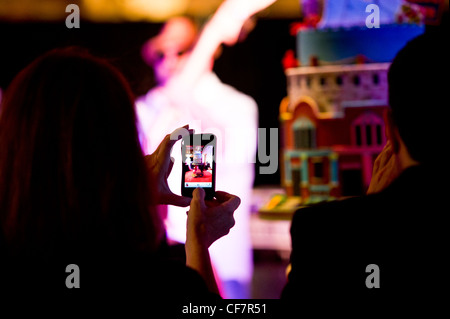 Woman taking photo with iphone of Ace of Cakes Duff Goldman playing string bass performance at AVAM in Baltimore, MD Stock Photo