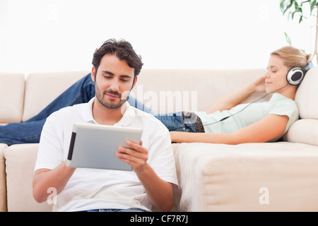 Man using a tablet computer while his girlfriend is listening to music Stock Photo